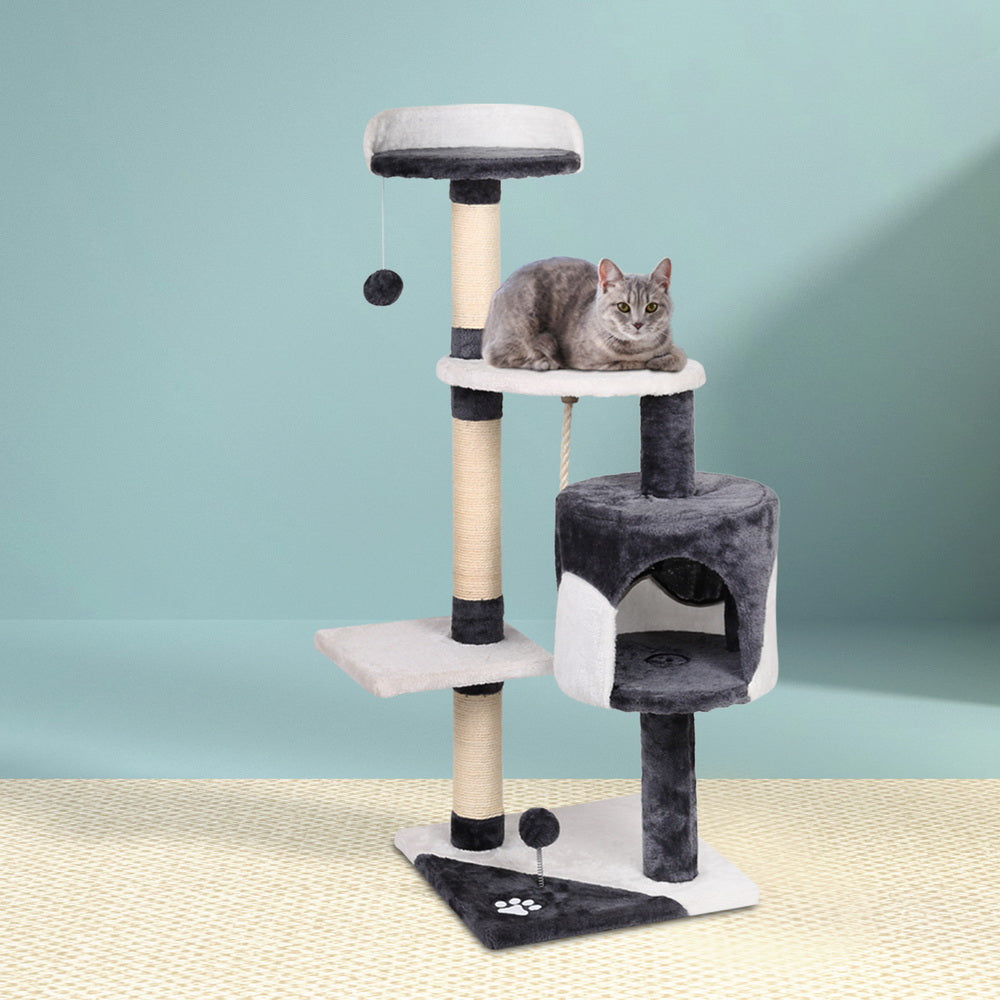 "Cat lounging on a perch with scratching post and cat toy ball nearby"